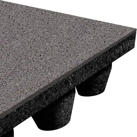 A close-up of the ECORE Athletic ECORE Performance dBTile Rubber Tile - 2.5" Acoustic Flooring shows its textured, speckled black surface, thick edge, and multiple raised cylindrical supports on the underside.