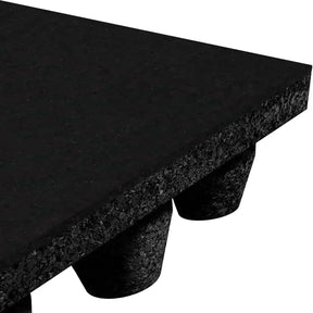 Close-up of ECORE Athletic’s Performance dBTile Rubber Tile - 2.5" Acoustic Flooring, showing its thick, textured black surface and cylindrical feet for elevation and support. Only a corner of the mat and some feet are visible.
