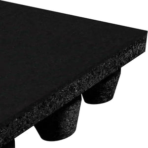 Close-up of ECORE Athletic’s Performance dBTile Rubber Tile - 2.5" Acoustic Flooring, showing its thick, textured black surface and cylindrical feet for elevation and support. Only a corner of the mat and some feet are visible.