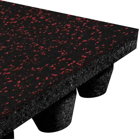 Close-up of the ECORE Performance dBTile Rubber Tile - 2.5" Acoustic Flooring by ECORE Athletic, featuring a thick black rubber build with red speckles, a textured upper surface, and cylindrical feet, shown from an angled side view.