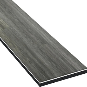 A close-up of one rectangular ECORE Heritage Motivate Vinyl Plank - 7mm PVT Performance Flooring by ECORE Athletic showcases its gray wood-look, textured grain, and visible layered construction along the edges.