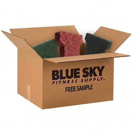 An open cardboard box labeled ECORE Athletic FREE Sample Rubber Paver reveals three rubber flooring tiles in green, red, and black.