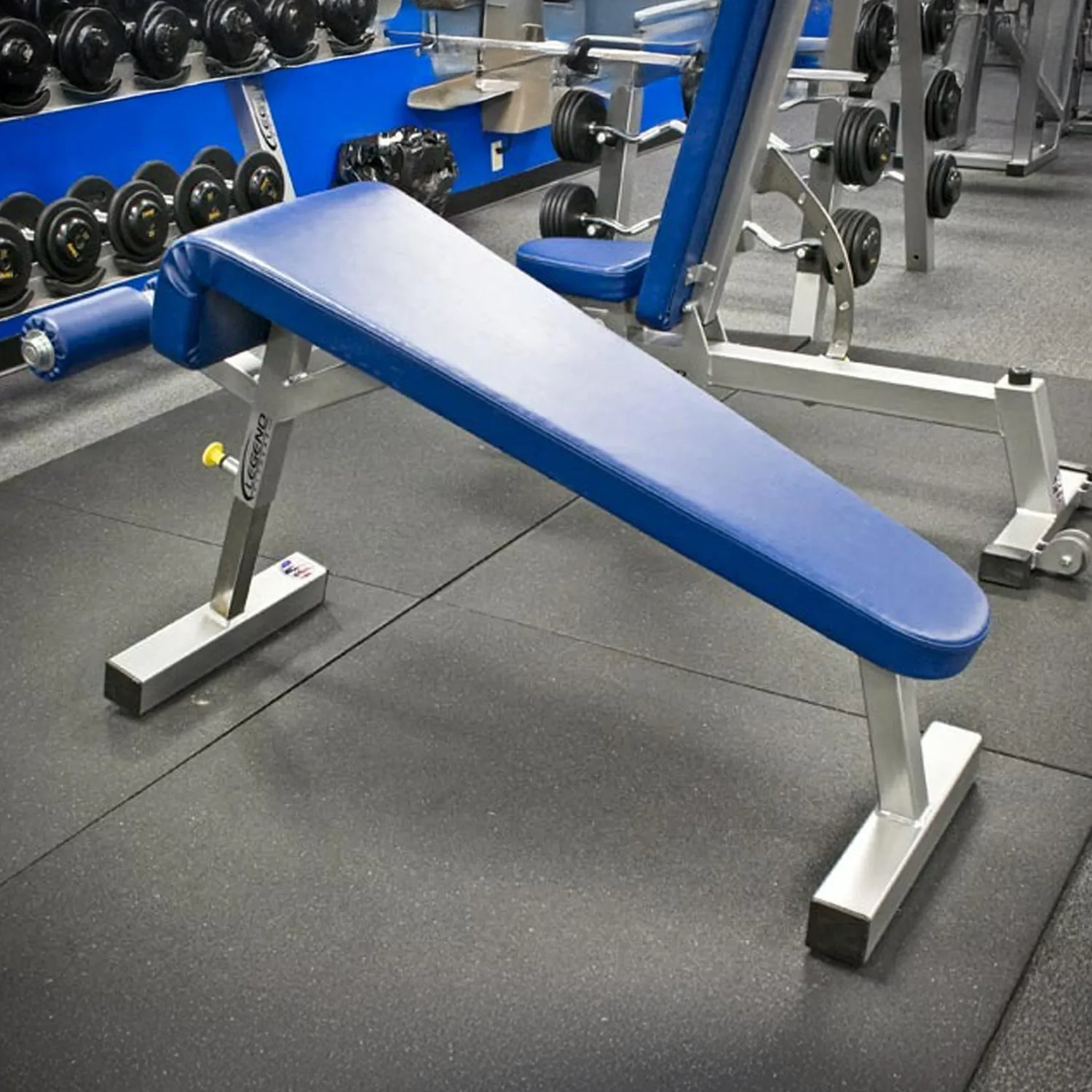 Blue weight bench in a gym setting with weights in the background