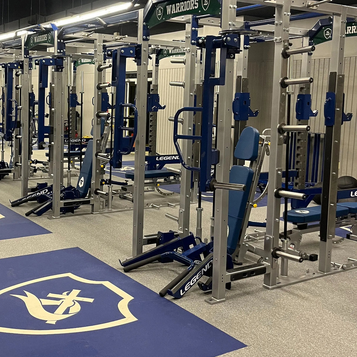 Blue and gray gym equipment with 'Warriors' branding in a weight room