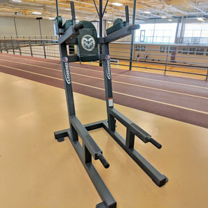 A gray metal crunch chair with green upholstery with a 'CSU Rams' logo on it in a fitness center setting