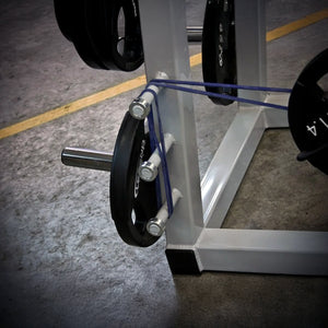 Close-up of a weightlifting machine with rubber bands and weights on a concrete floor.