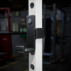 Metal barbell hook on a white squat rack upright