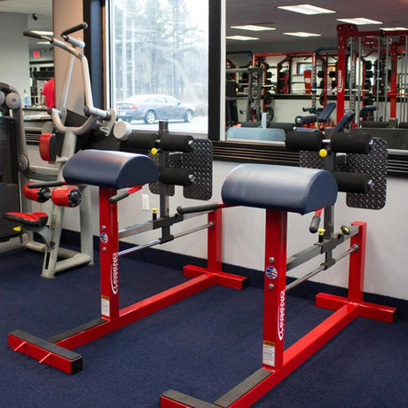 Two red and blue glute ham developer fitness machines in a gym setting