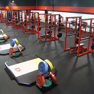 Gym interior with weightlifting equipment including barbells and weight plates.