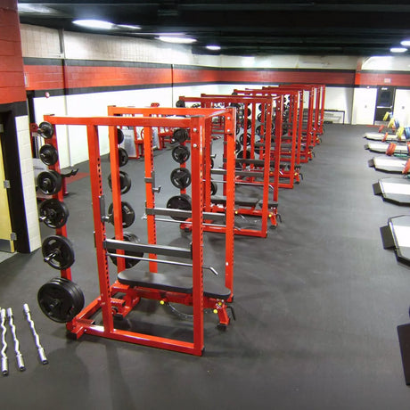 Gym with red weight racks and weight plates on a gray floor.
