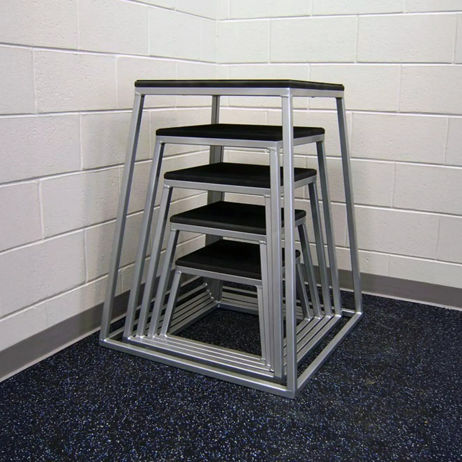 Set of metal step stools with black platforms stacked against a tiled wall.