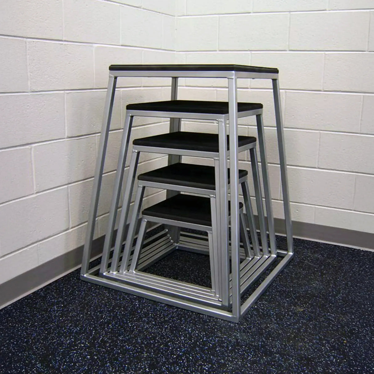 Set of metal step stools with black platforms stacked against a tiled wall.