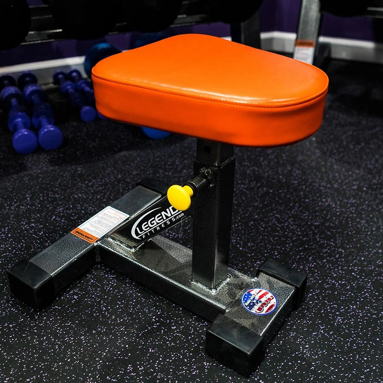 Orange weight bench seat with black metal frame on a gym floor.