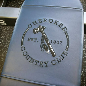 A blue gray bench pad with 'Cherokee Country Club' embroidered on it