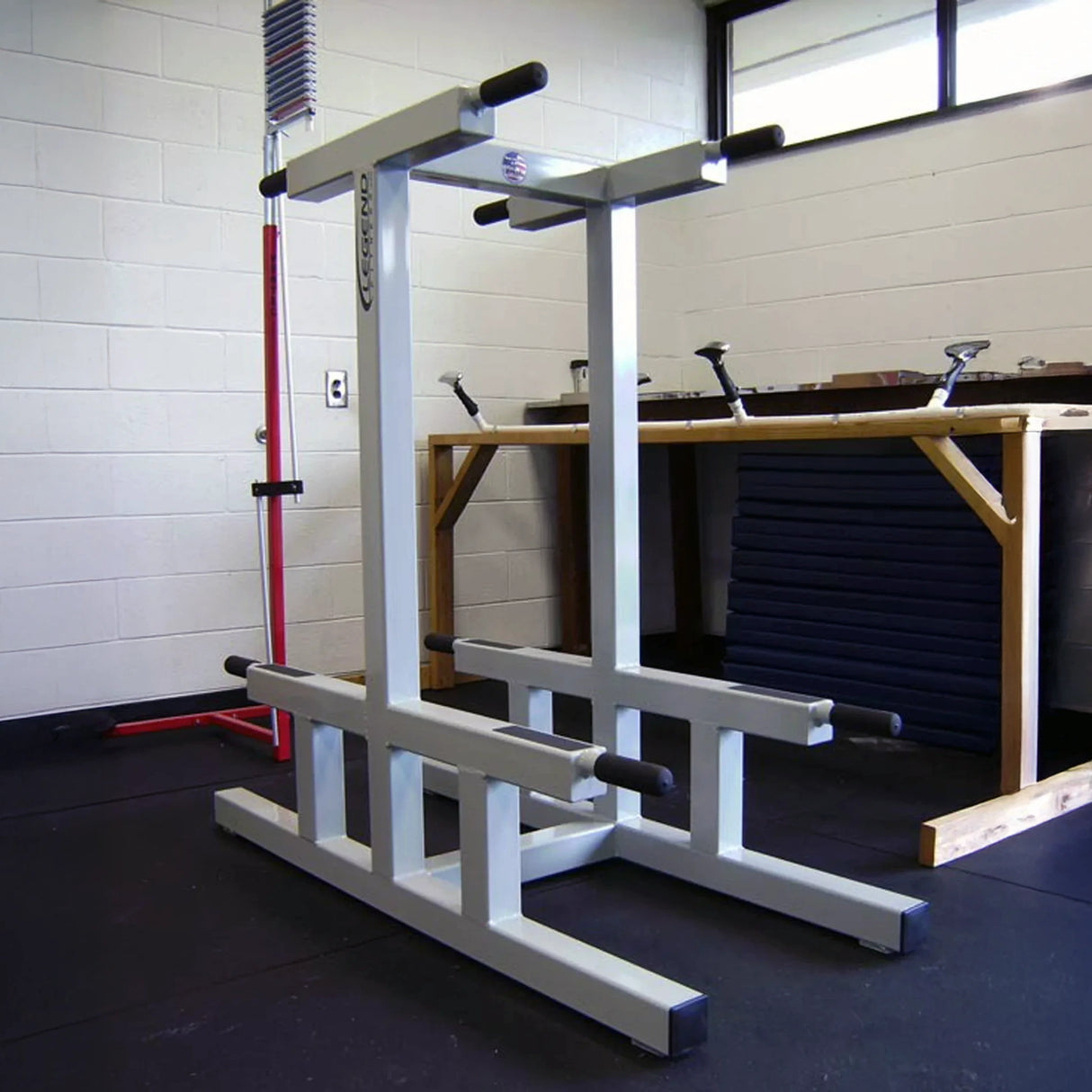 A white metal dip stand in a gym setting