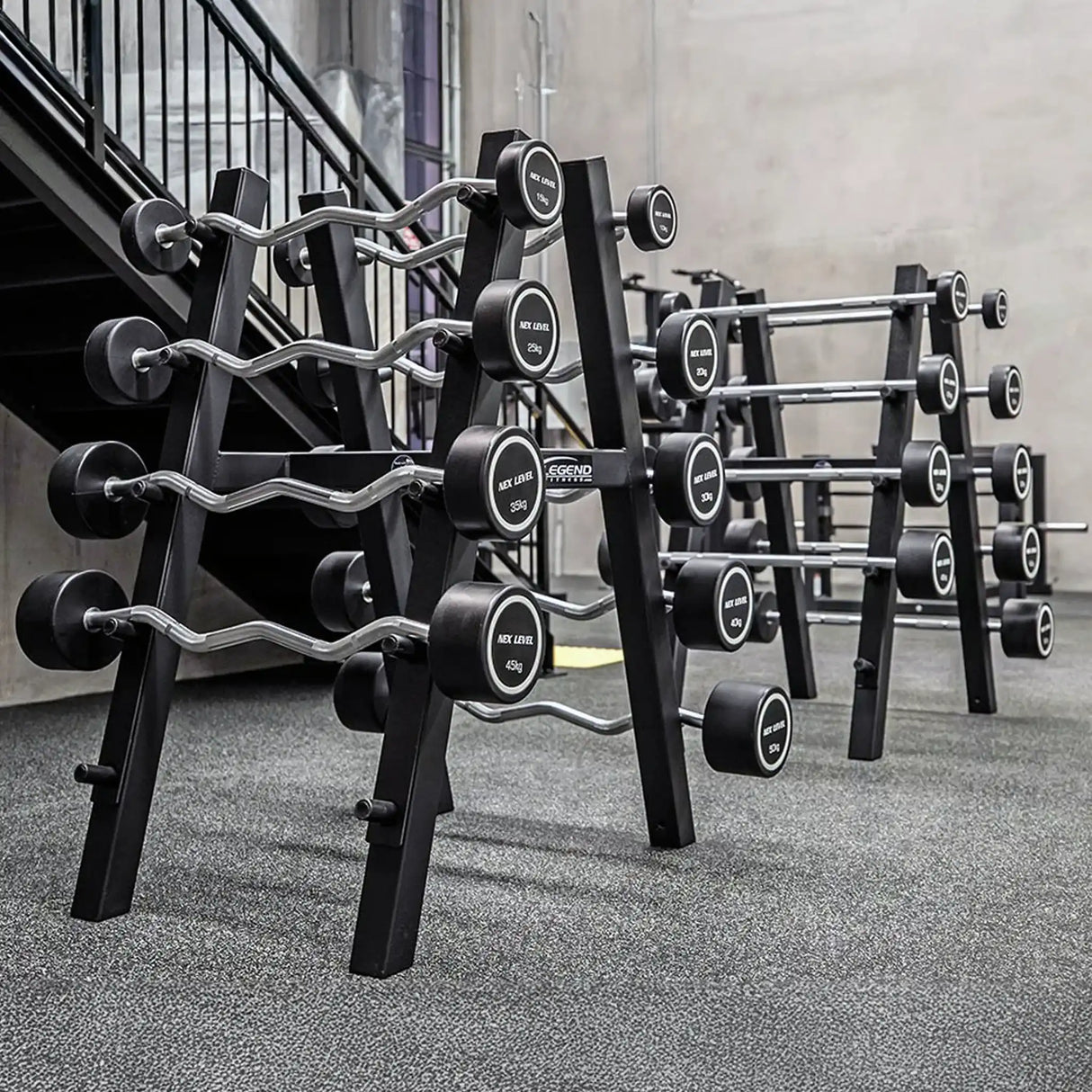 Two black barbell storage racks with barbells on them in a gym setting