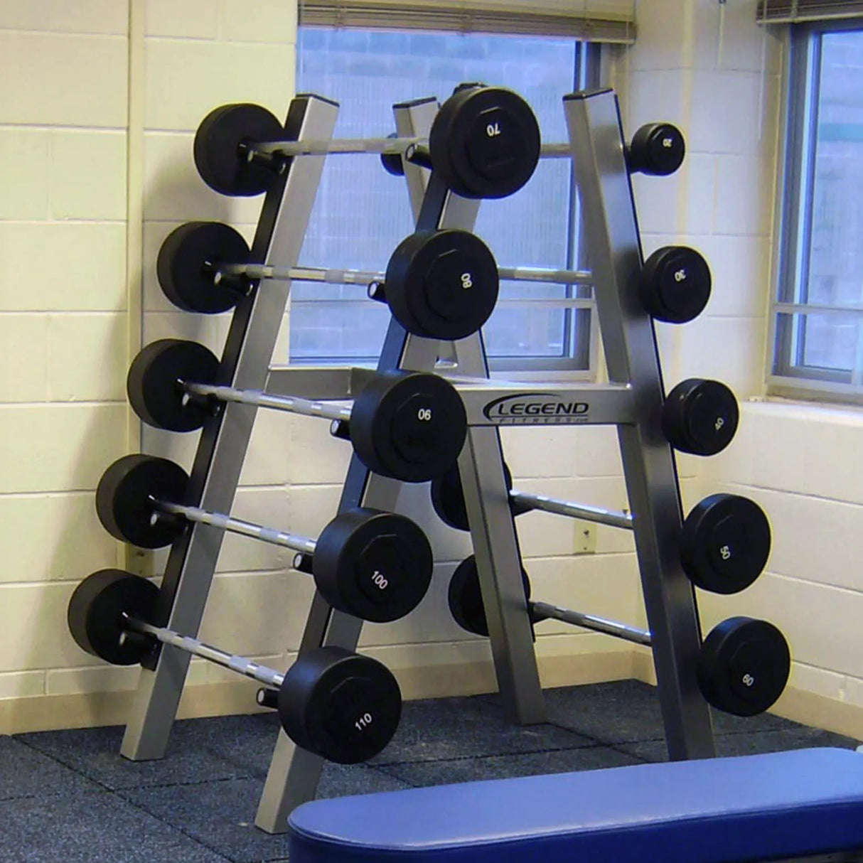 A silver barbell storage rack with 10 barbells stored on it in a gym setting