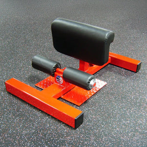 An orange sissy squat fitness machine with black pads on a black and white gym floor