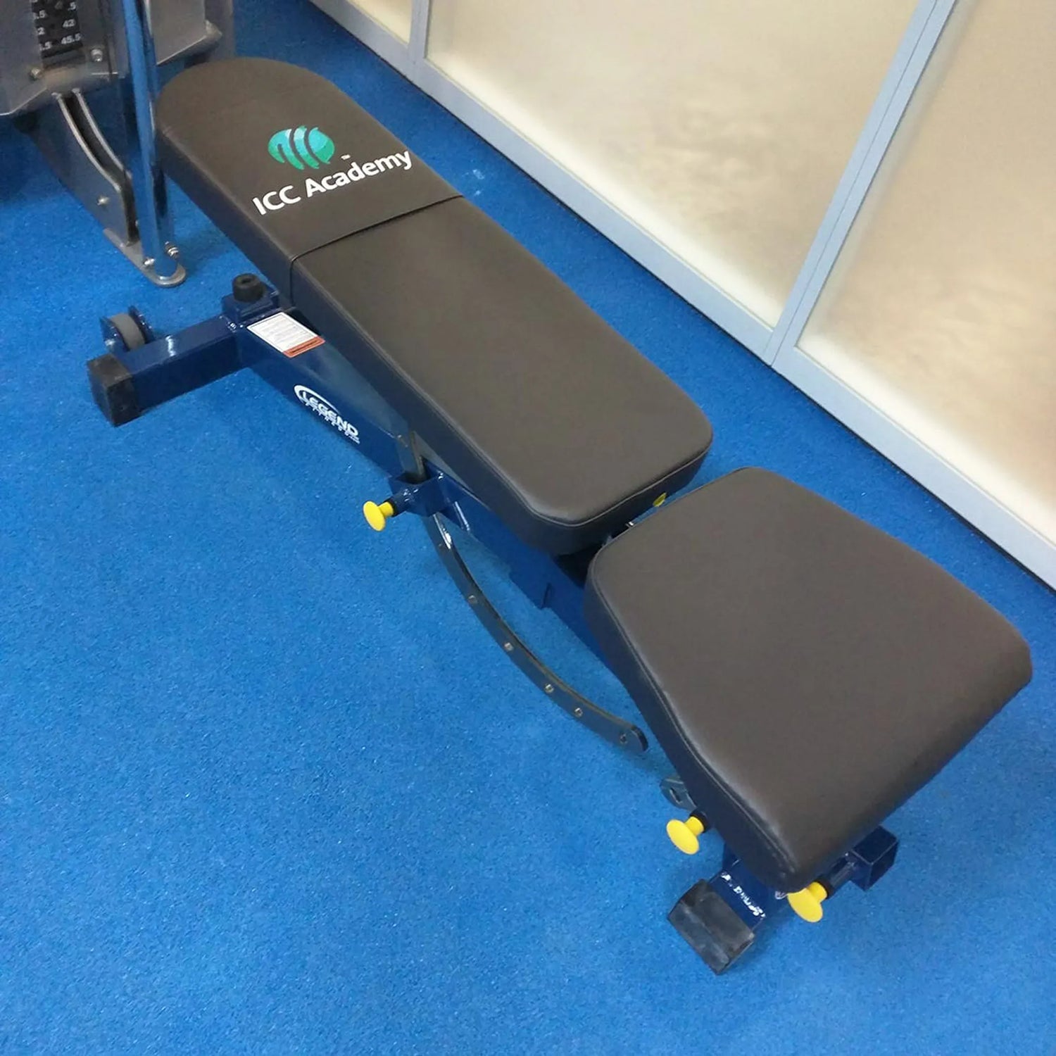 Weight bench with ICC Academy logo on a blue floor