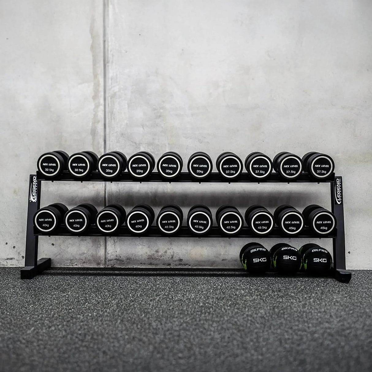 Set of dumbbells on a rack against a concrete wall.