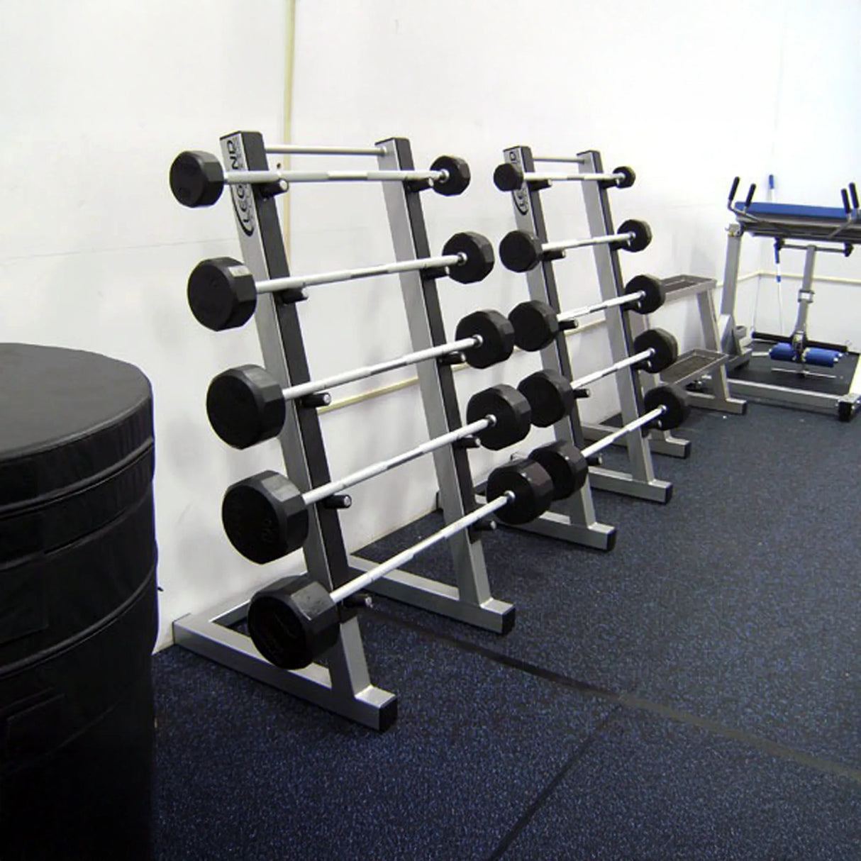 2 silver barbell storage racks side by side with barbells on them in a gym setting