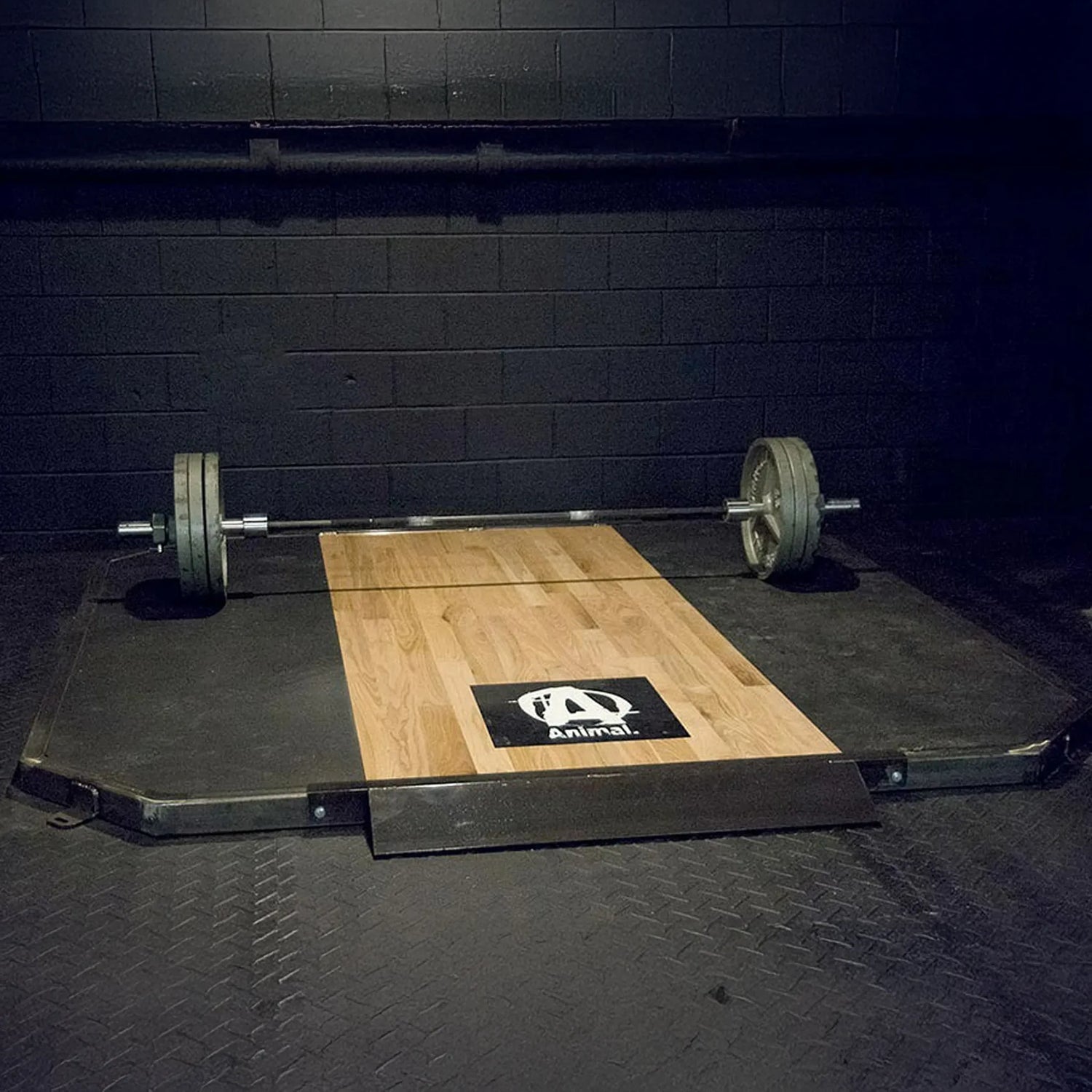 Weightlifting platform with a barbell on a dark floor and black wall