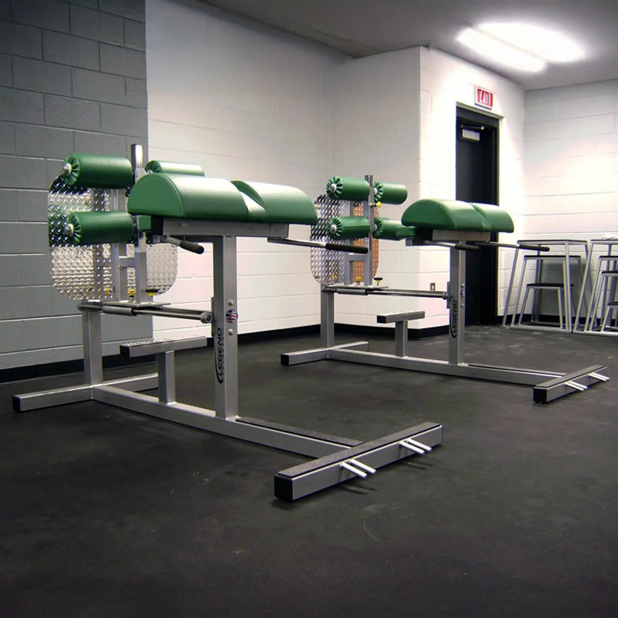Silver glute ham developer fitness machines with green pads in a gym setting