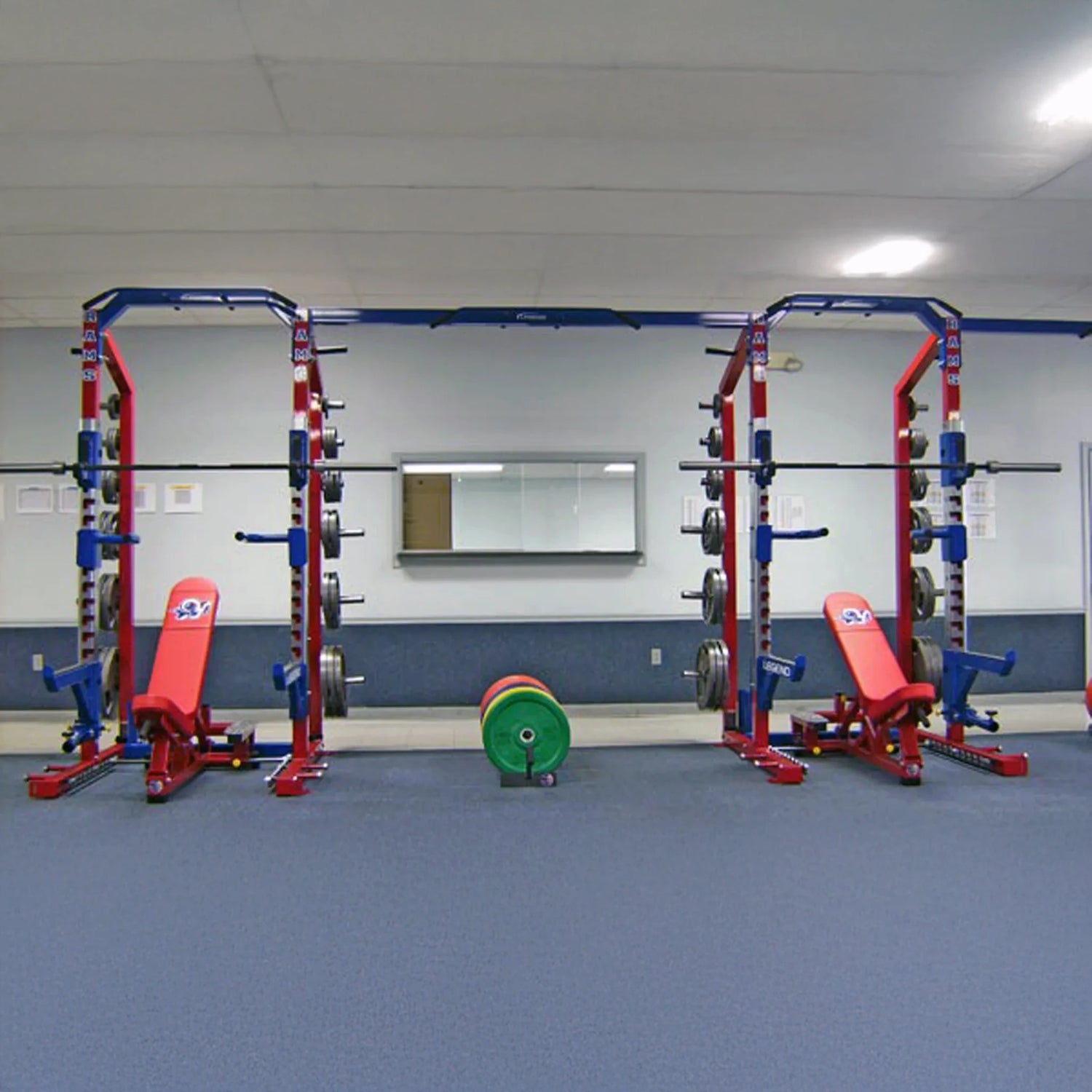Gym with weight lifting equipment including red weight benches and blue weight racks.