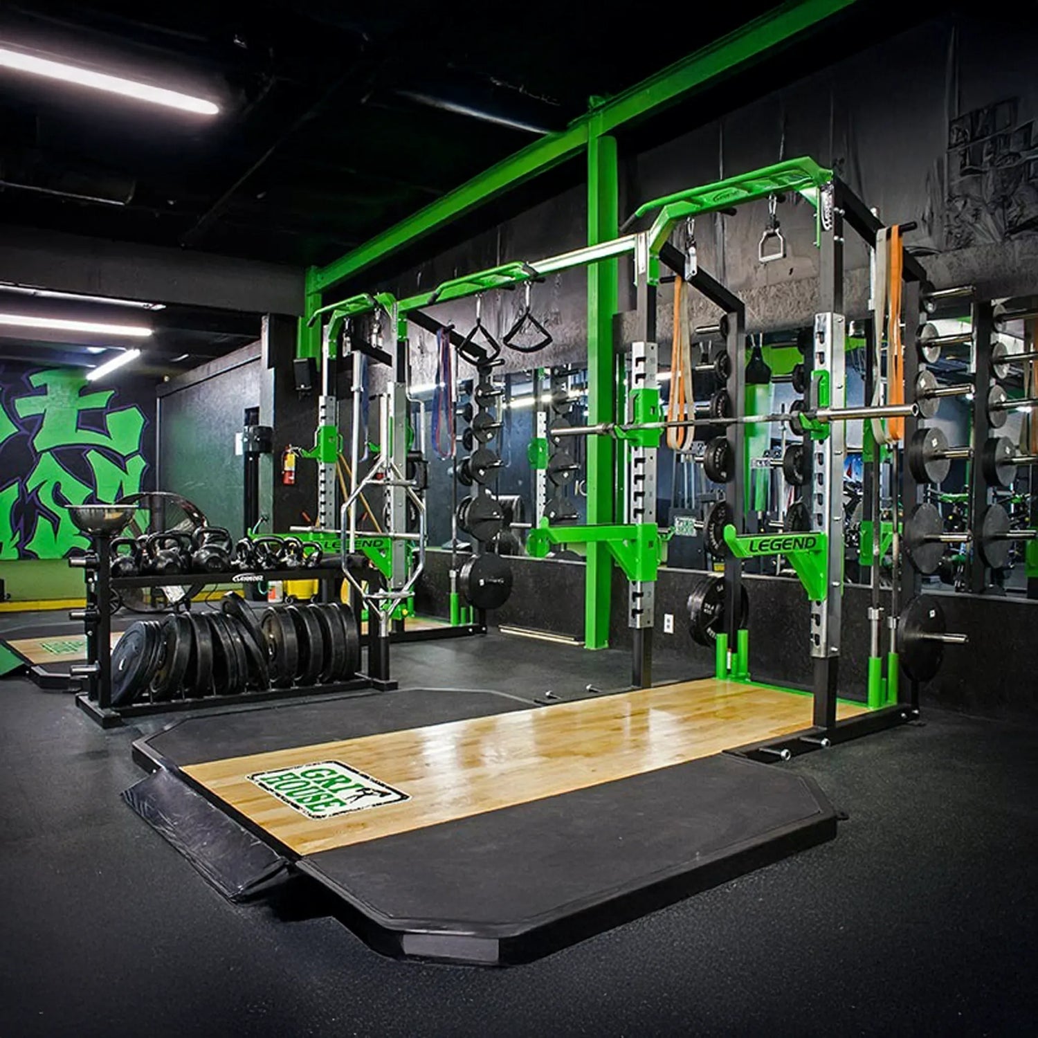 Gym interior with weightlifting equipment, including a power rack and weight plates.