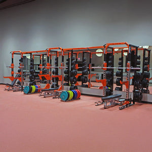 Gym equipment including weight racks and benches on a red orange floor.