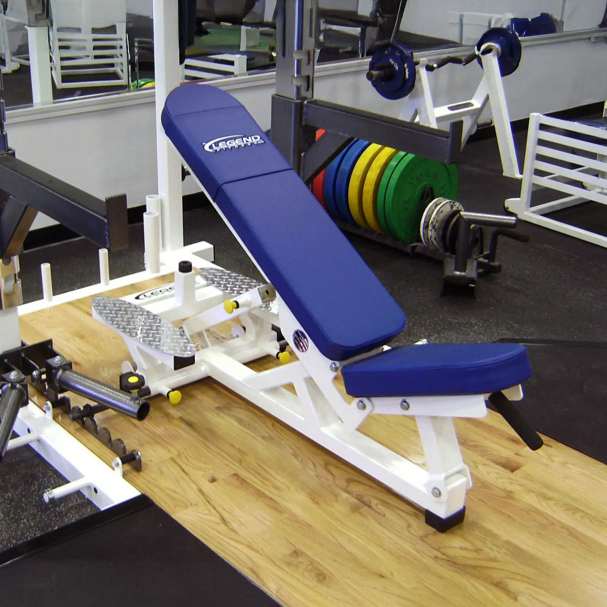Blue weight bench with white frame on a wooden platform in a gym setting