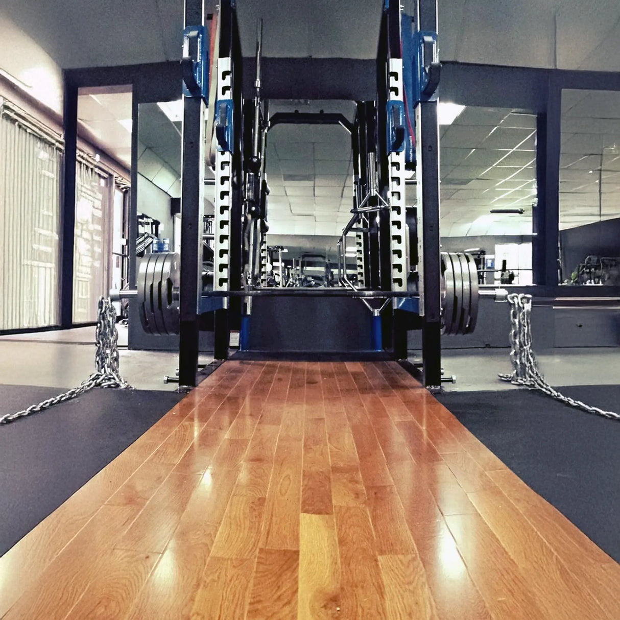Wooden platform in a gym with weightlifting equipment in the background