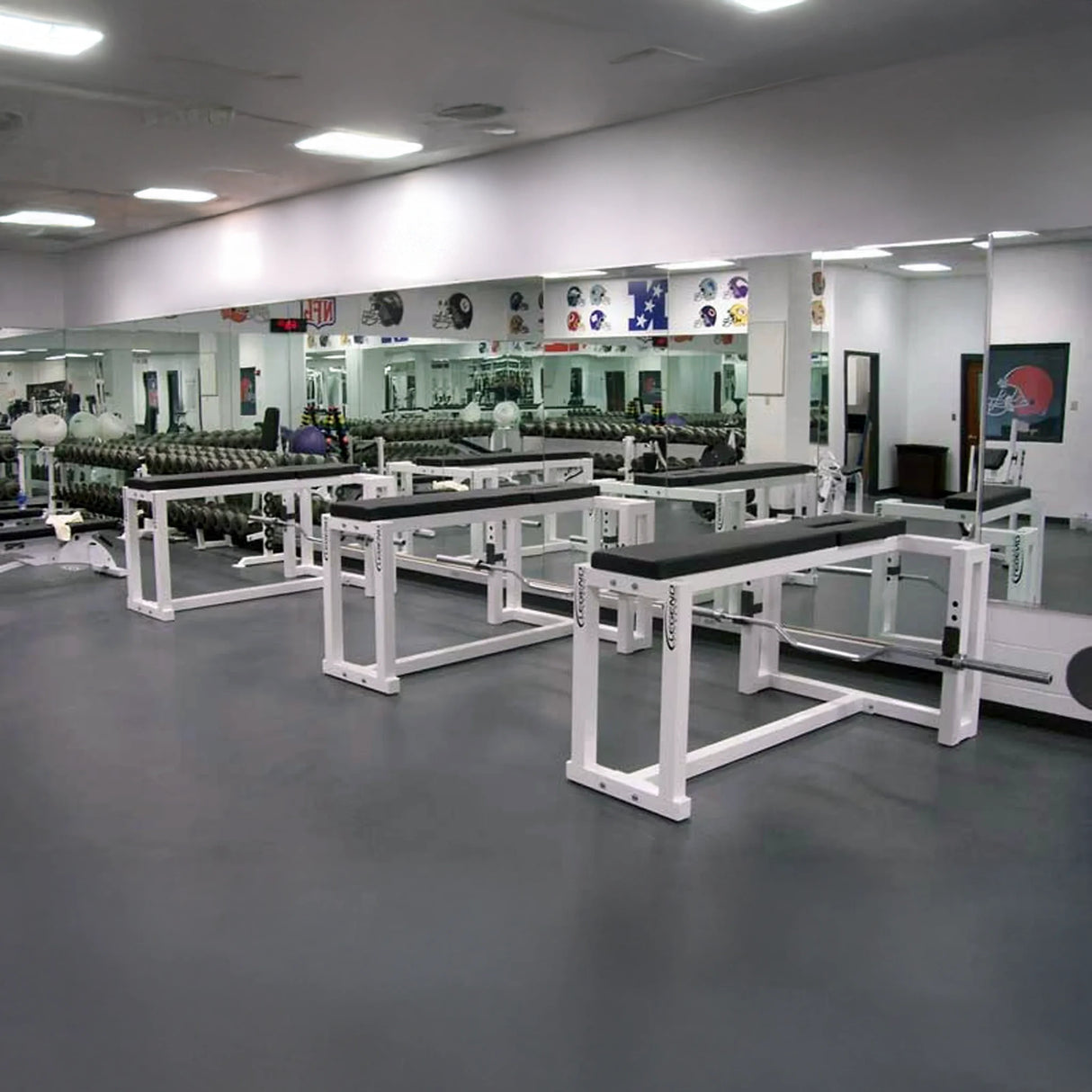 A row of black and white prone row machines in a gym setting