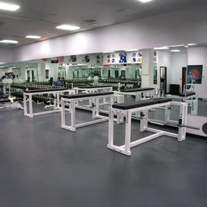 A row of black and white prone row machines in a gym setting