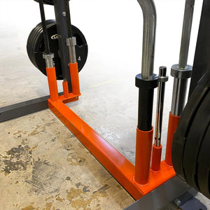 Gym equipment with orange safety bars on a concrete floor