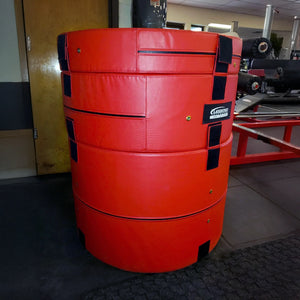 A red cylindrical plyometric cushion in a gym setting