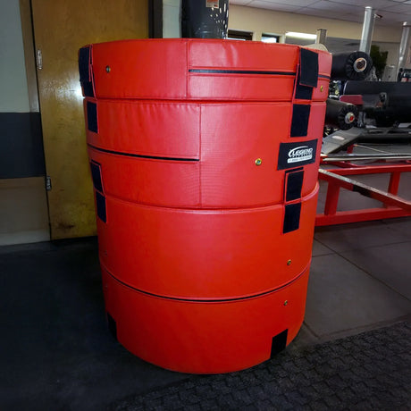 A red cylindrical plyometric cushion in a gym setting