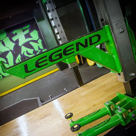 A metal safety arm mounted to a squat rack with 'Legend' branding