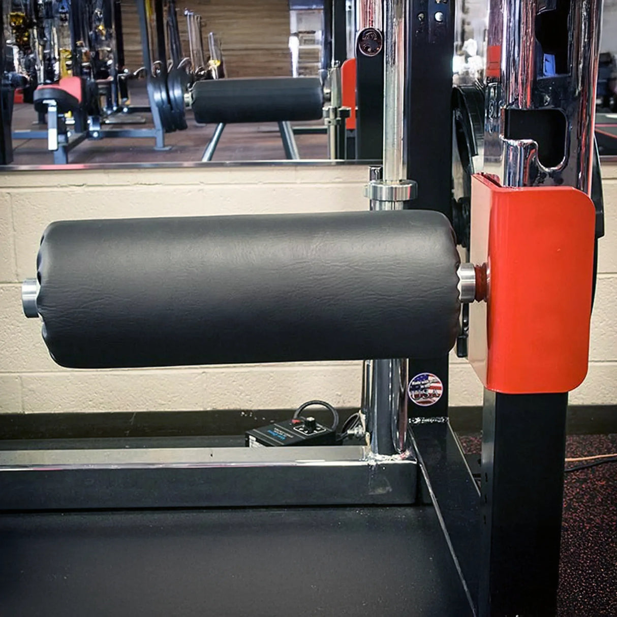 A black leg roller pad mounted onto a squat rack