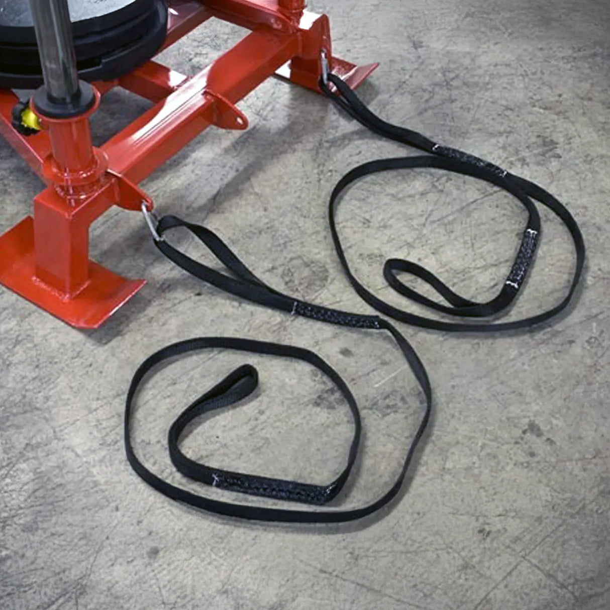 Red metal equipment with black straps connected to it on a concrete floor