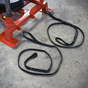 Red metal equipment with black straps connected to it on a concrete floor