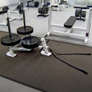 A white fitness sled with black weight plates on it in a gym setting