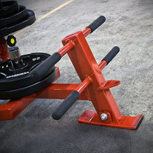 Red metal equipment with black weight plates on it on a concrete floor