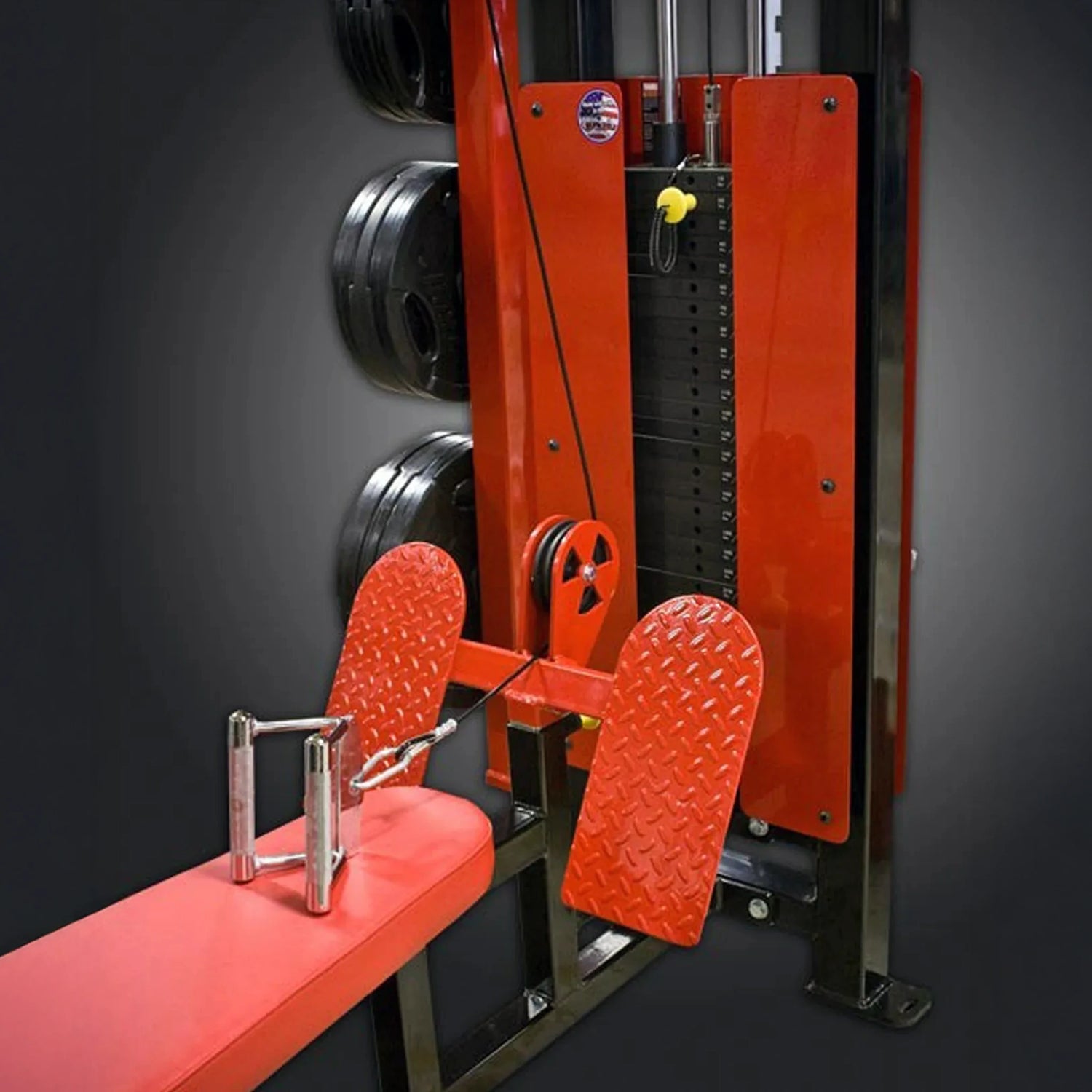 Red weightlifting machine with foot platforms on a dark background
