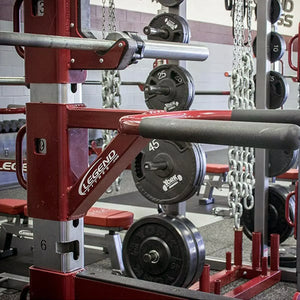 A red and black dip attachment mounted to the side of a squat rack