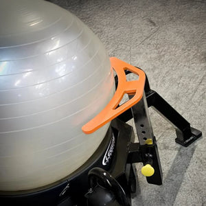 A white exercise ball on a piece of fitness equipment on a concrete floor