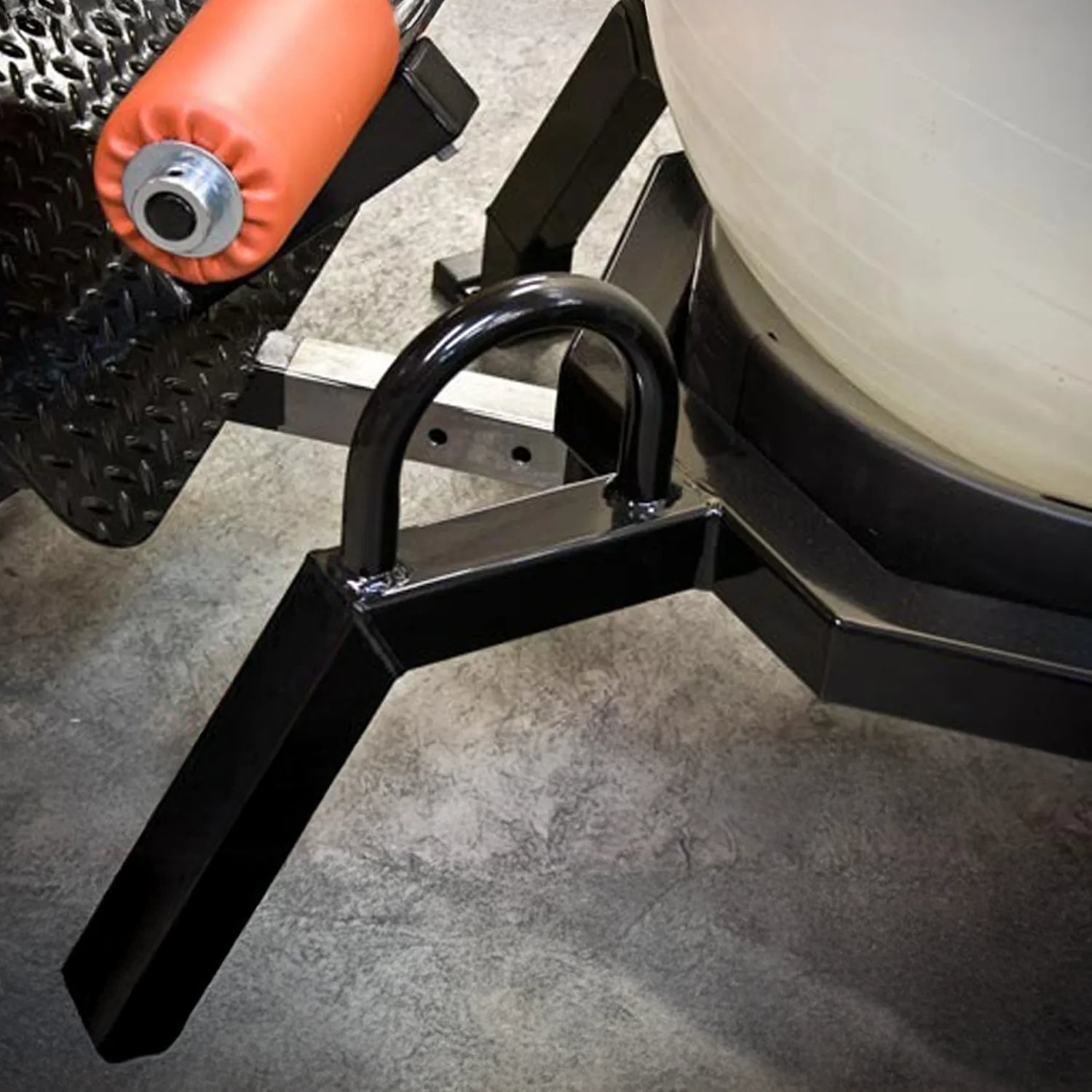 Close-up of a black metal frame of a piece of fitness equipment, with a concrete floor in the background.