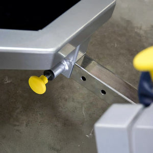 Close up of a gray metal frame with a yellow pop-pin on a concrete floor