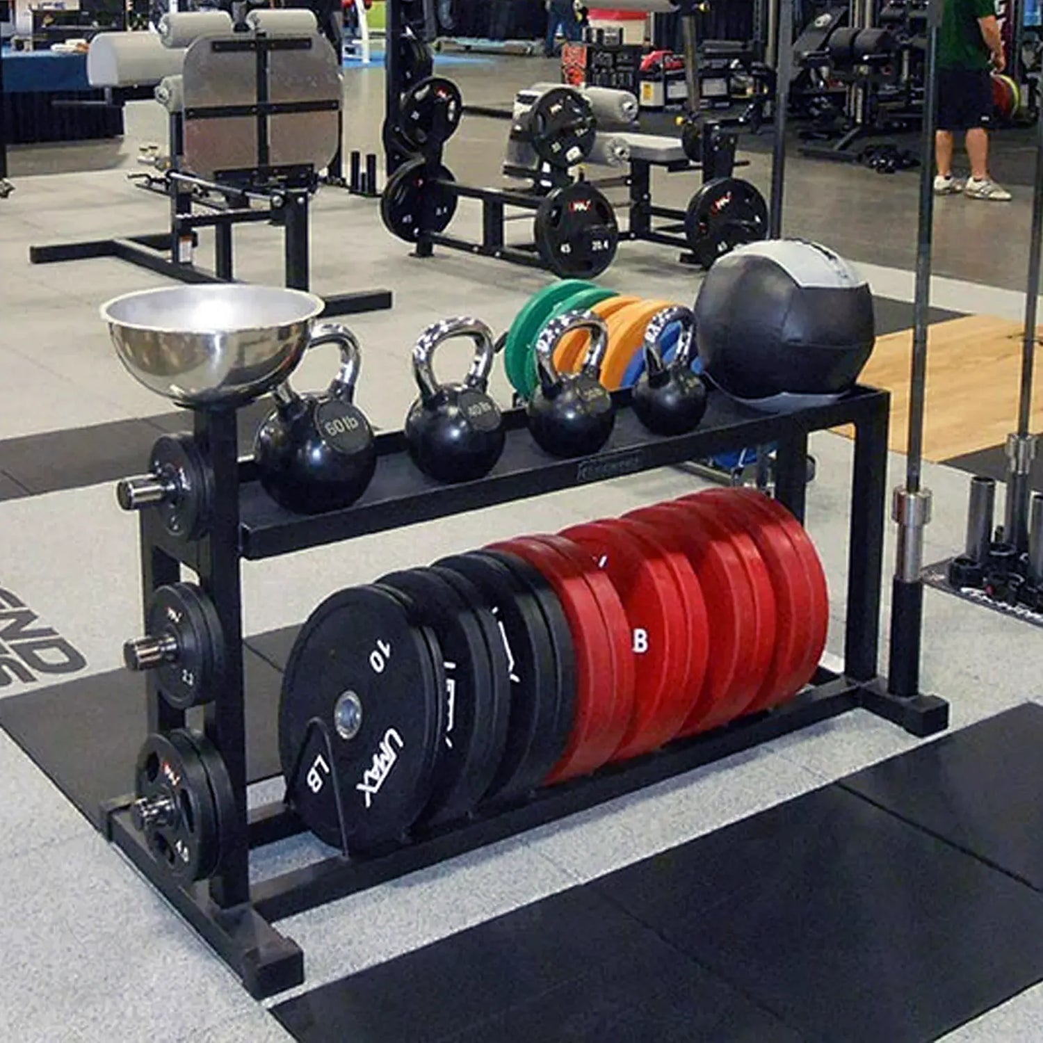 A black weight lifting storage rack with kettle bells on the top shelf and bumpers on the bottom shelf