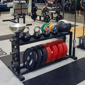 A black weight lifting storage rack with kettle bells on the top shelf and bumpers on the bottom shelf